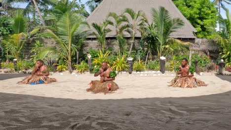 Männliche-Fidschi-tänzer,-Die-Auf-Dem-Sand-In-Grasröcken-Sitzen-Und-Fidschi-Aufführen