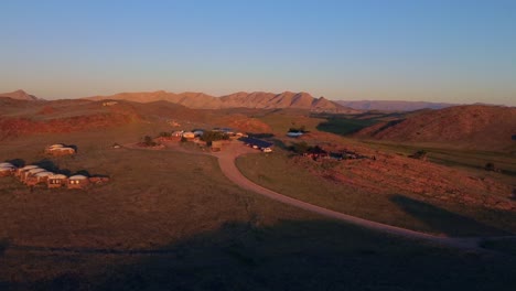 Drohnenaufnahme-Eines-Afrikanischen-Dorfes-Bei-Sonnenuntergang---Drohne-Kreist-über-Steppe-In-Namib-Naukluft