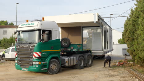 Wide-load-heavy-goods-vehicle-entering-construction-site-carrying-modular-home