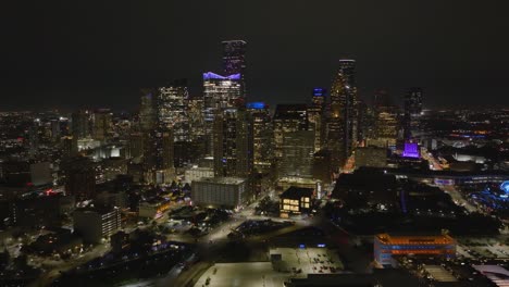 Aerial-view-around-the-cityscape-of-downtown-Houston,-during-nighttime-in-Texas,-USA---wide,-panoramic,-drone-shot
