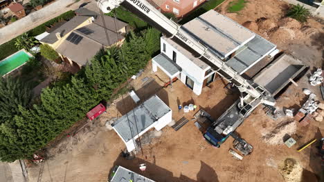 Rising-up-crane-boom-arm-installing-modular-home-on-construction-site-lot-aerial-view