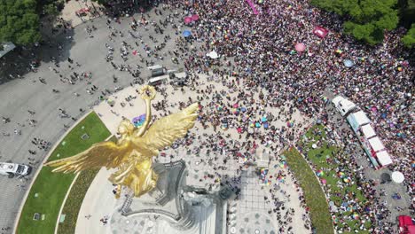 Aerial-flyover-tilts-over-angel-statue-to-Pride-parade-in-Mexico-City