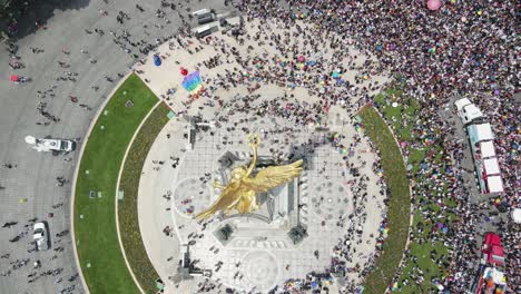 Aerial-tilt-shift-over-gold-angel-statue-to-Pride-Day-crowd-on-street