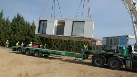 Construction-workers-removing-modular-smart-home-unit-from-truck-with-crane-hoist