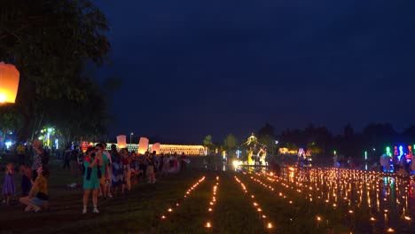 People-lighting-up-floating-lanterns-at-lake-with-candle-lights-during-Yi-Peng