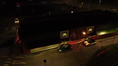 Cars-queue-at-McDonalds-fast-food-drive-through-at-night-in-Northern-UK-town-aerial-view