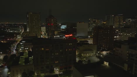 Aerial-view-towards-the-Bayou-lofts-sign-on-top-of-the-building,-night-in-Houston,-USA---circling,-drone-shot