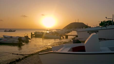 Orangefarbener-Sonnenuntergangsstrand-Mit-Angelsteg,-Seevögeln-Und-Motorbooten-Auf-Der-Tropischen-Insel