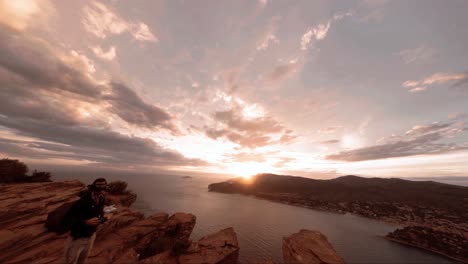 FPV-Aerial-people-relaxing-on-top-of-the-cliffs-in-cassis,-France-during-golden-hour