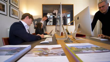 Panning-shot-showing-businessman-and-businesswoman-working-architect's-office-with-apple-computer---slow-motion