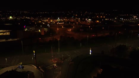 Fliegen-über-Die-Stadtautobahn-In-Uk-Und-Mcdonalds-Fast-Food-Fahren-Durch-Die-Nachts-Beleuchtete-Luftrückbahnansicht