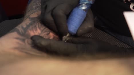 Close-up-of-tattoo-machine-being-used-on-an-arm-and-cleaned-afterwards
