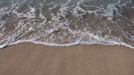Small-waves-Lapping-against-Sandy-beach,-Sun-Glistening-on-Surface-on-Sunny-Day,-Waikiki,-Hawaii
