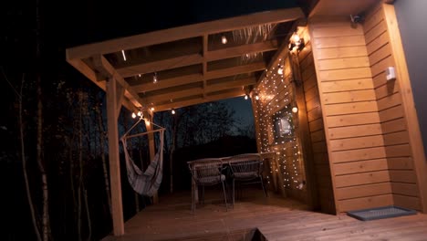Cozy-Wooden-Cabin-Balcony-with-Hammock-and-Warm-Lights-at-Nighttime