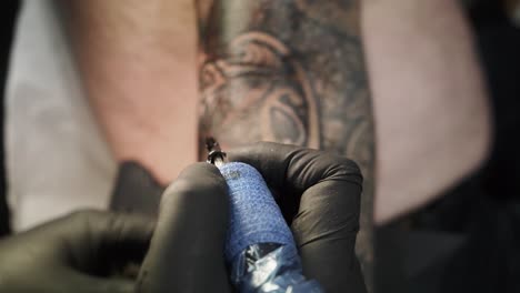 Close-up-of-needle-machine-of-tattoo-artist-while-cleaning-his-client-his-arm