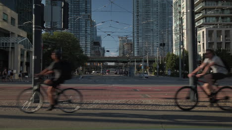 Exterior-wide-shot-of-westbound-cyclists-passing-through-the-intersection-at-Queens-Quay-and-Spadina-Avenue-in-Toronto