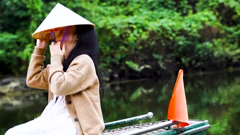 Vietnamese-Tourist-Putting-On-Conical-Hat-On-Boat-At-Ninh-Binh