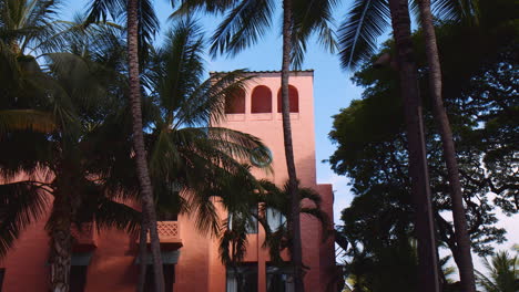 Torre-De-Hotel-Rosa-Con-Palmeras-De-Coco-Esbeltas-En-Un-Día-Soleado-En-Waikiki,-Oahu