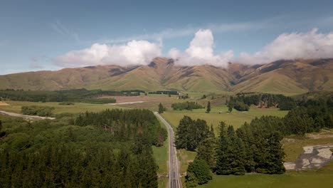 Aerial---State-Highway-8-leading-through-farm-land-and-high-mountains-in-New-Zealand