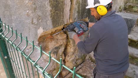 Hand-held-shot-of-a-worker-drilling-away-at-a-hole-in-the-wall