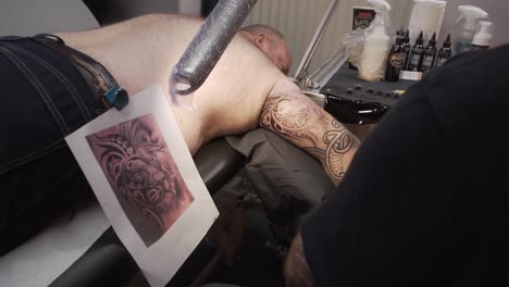 Man-laying-down-on-the-tattoo-table-during-the-session-of-finishing-his-sleeve