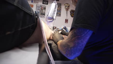 In-between-shot-of-someone-his-arm-being-tattooed-by-tattoo-artist
