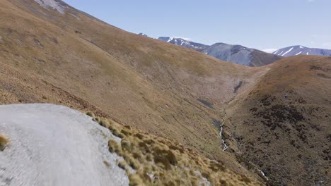 Three-men-hiking-up-a-steep,-dusty-mountain-road-in-Mackenzie,-New-Zealand