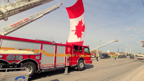 Toronto-Feuerwehr-Gedenkzeremonie-Lastwagen-Hängen-Riesige-Kanadische-Flaggen-Mit-Flugzeugschatten,-Während-Sie-über-Ihnen-Vorbeifliegen