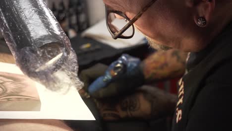 Tatoo-artist-coloring-the-arm-with-the-tattoo-pistol-needle
