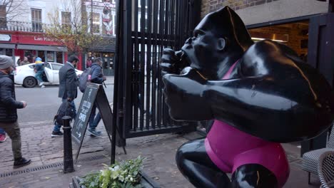 Close-up-shot-of-local-men-and-women-entering-winter-wonderland-in-London,-UK-with-black-gorilla-statue-along-the-side-at-daytime