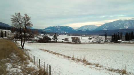 Majestic-Snow-Covered-Mountains-with-Crisp-Grass-Farmland-Near-Little-Fort,-British-Columbia,-Canada---Captivating-Winter-Tracking-Shot
