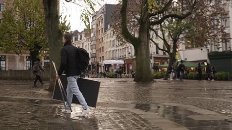 Hombre-Caminando-Por-El-Grasmarkt-En-Bruselas-Con-Equipo-De-Billar