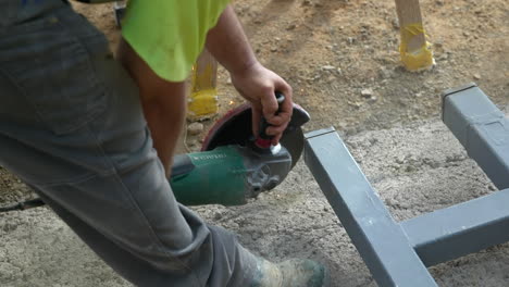 Slow-motion-labourer-with-cutting-wheel-making-sparks-on-steel-tube-frame-on-construction-site