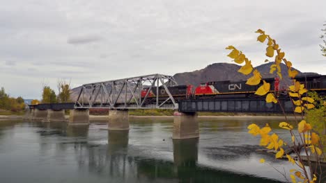 Ein-Güterzug,-Der-An-Einem-Bewölkten-Herbsttag-Den-South-Thompson-River-über-Die-CNR-Brücke-In-Der-Nähe-Des-Riverside-Park-östlich-Der-Innenstadt-Von-Kamloops-überquert