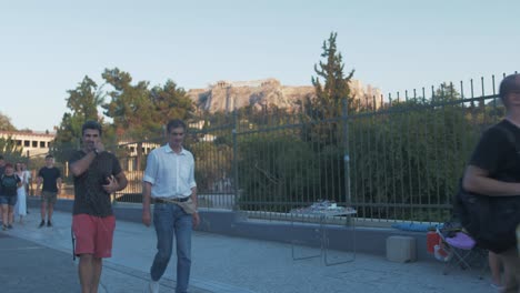People-walk-in-front-of-distant-Acropolis-during-golden-hour