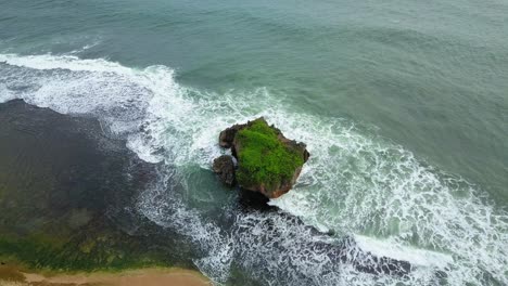 Aerial-shot-of-waves-crashing-on-the-coral-rock-near-the-beach