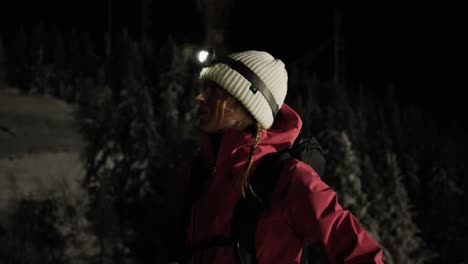Beautiful-Young-Woman-Camper-With-A-Headlamp-Standing-Looking-Around-In-The-Forest