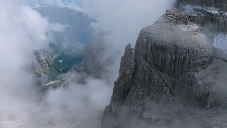 Aerial-flight-through-dense-clouds-revealing-mountains-and-green-valley-in-Dolomites
