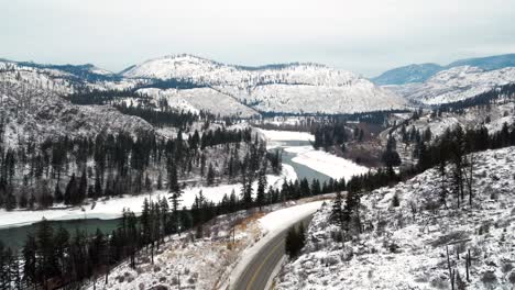 Winter-in-British-Columbia:-Aerial-Shot-Follows-Yellowhead-Highway-5-Through-the-Frozen-North-Thompson-River-Valley-near-Kamloops,-Snowy-Landscape-Panoramic-View