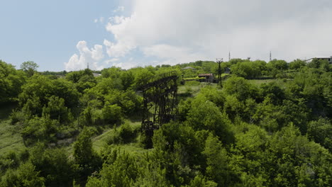 Rusty-material-ropeway-pylon-and-hanging-container-on-grassy-hillside