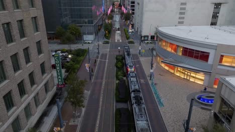 Aerial-view-tracking-a-tram-on-the-Main-street-of-Houston,-USA---tilt,-drone-shot