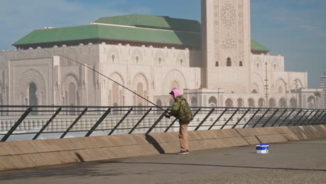 Fisherman-fishing-in-front-of-Hassan-II-mosque-Casablanca-Morocco