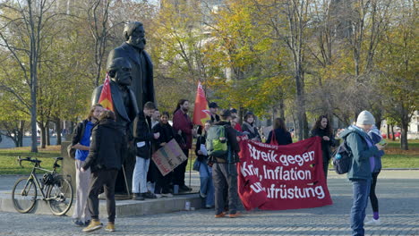 Young-protesters-standing-taking-photograph-in-Berlin-public-park-in-front-of-historical-statue