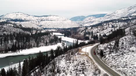 Semi-Trucks-on-Yellowhead-Highway-5-in-British-Columbia:-An-Aerial-Moving-Left-Perspective-of-Transportation-Through-the-Frozen-North-Thompson-River-Valley,-Kamloops,-Scenic-Forest,-Snowy-Mountainous