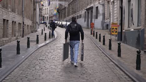 Hombre-En-Cámara-Lenta-Caminando-Por-Las-Calles-De-Bruselas-Con-Equipo-De-Billar-En-Sus-Manos