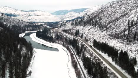 Snowy-British-Columbia:-A-Follow-Perspective-of-Trucks-and-Cars-on-Yellowhead-Highway-5-Next-to-the-Partially-Snow-covered-North-Thompson-River-Near-Kamloops,-Stunning-Snowy-Landscape-Panoramic-View