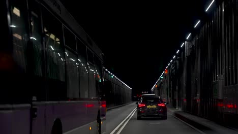 POV-Inside-Car-Driving-Through-Dark-Tunnel-Road-Near-Heathrow-Airport-With-Bus-Passing-On-The-Left