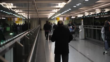 Gente-Caminando-Por-La-Pasarela-Interna-Que-Conecta-El-Aparcamiento-Con-La-Terminal-3-De-Heathrow-Por-La-Noche