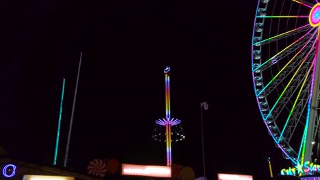 Low-angle-view-of-colourful-illuminating-moving-and-spinning-swing-ride-or-swing-carousel-on-background-of-night-dark-sky
