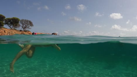 Szenische-Ansicht-Der-Wasserlinie-Des-Kleinen-Mädchens,-Das-Im-Kristallklaren-Tropischen-Meerwasser-Des-Palombaggia-strandes-Auf-Der-Insel-Korsika,-Frankreich,-Schwimmt